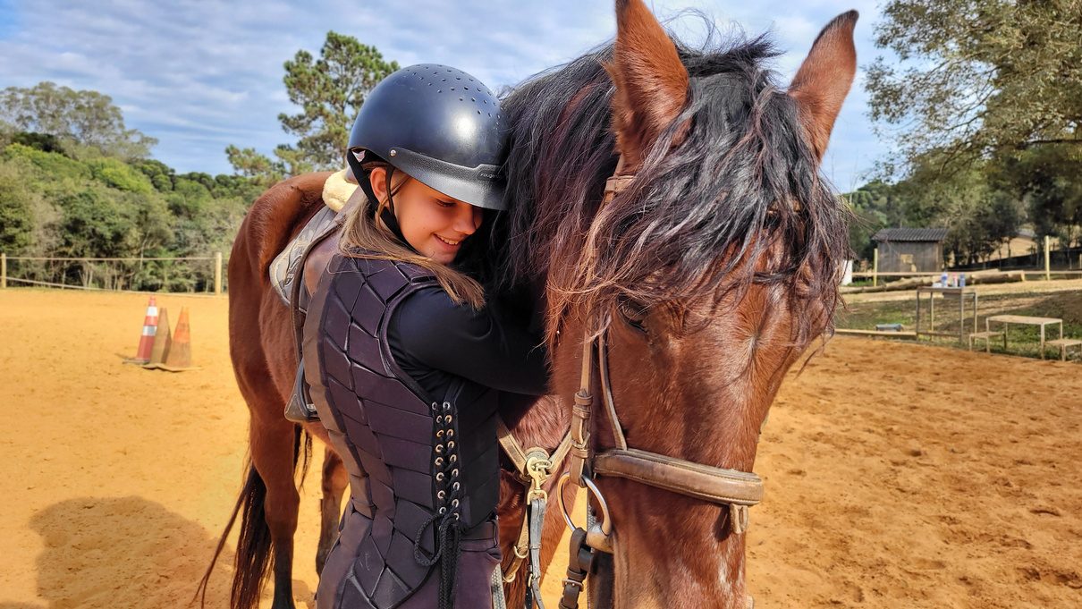 Aluna abraçando cavalo